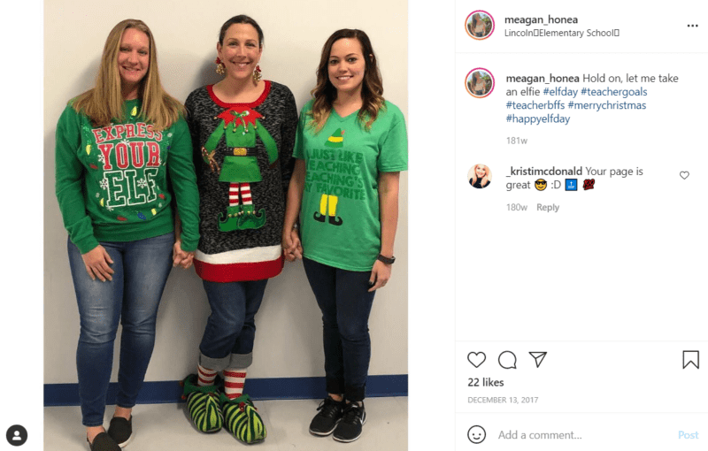 Three teachers pose in tacky Christmas sweaters in a school hallway