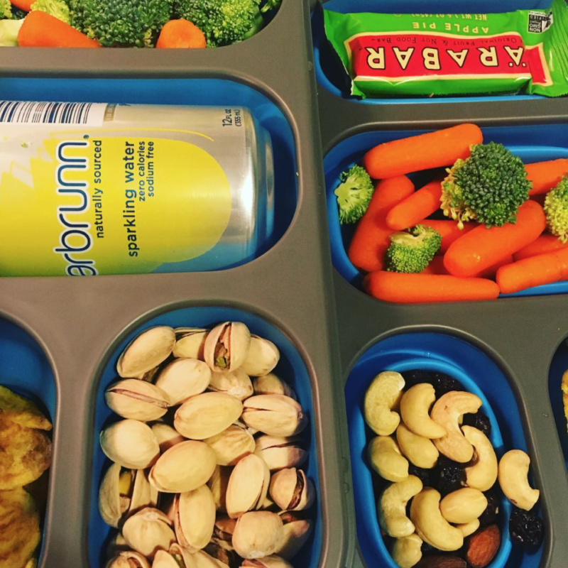 Pistachios, vegetables, and other snacks in a container
