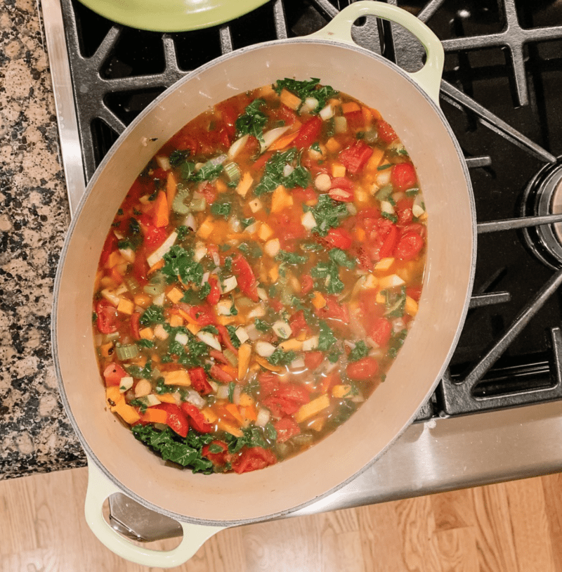 Large Dutch oven on a stovetop, filled with hearty vegetable soup