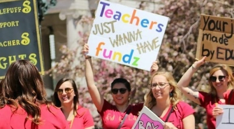 Teachers raising posters with words Teachewrs just wanna have funds