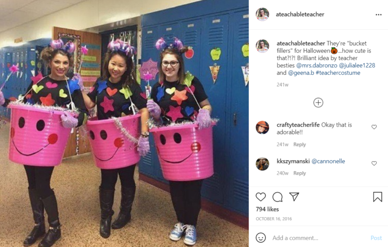 Three teachers in front of lockers in a school hallway each standing in a pink bucket with a smiling face draw onto it
