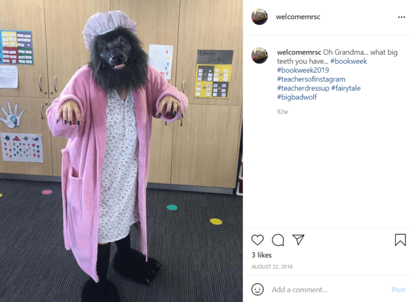 Teacher in a pink robe and wolf mask in a classroom