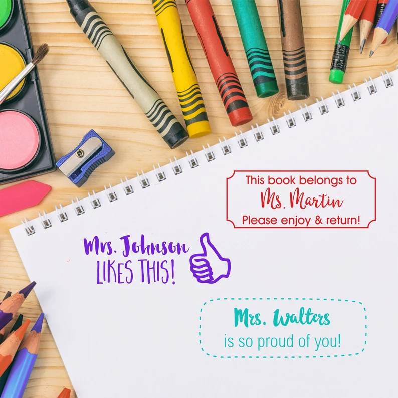 Several different personalized teacher stamps are shown on a pad of paper (personalized teacher gifts)