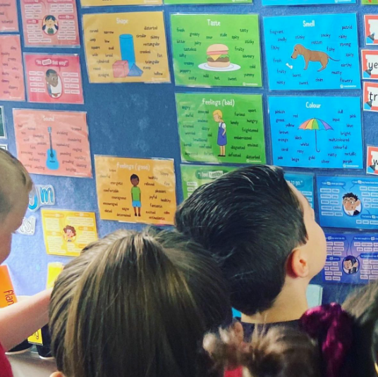 children gathering around a colorful bulletin board