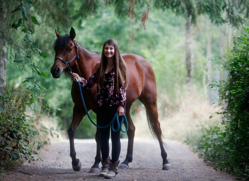 A teen girl and her horse standing in a lane
