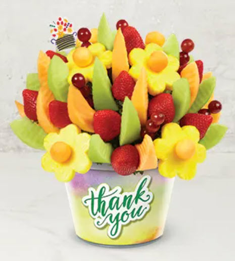 An edible arrangement of fruit in a tin reading Thank You