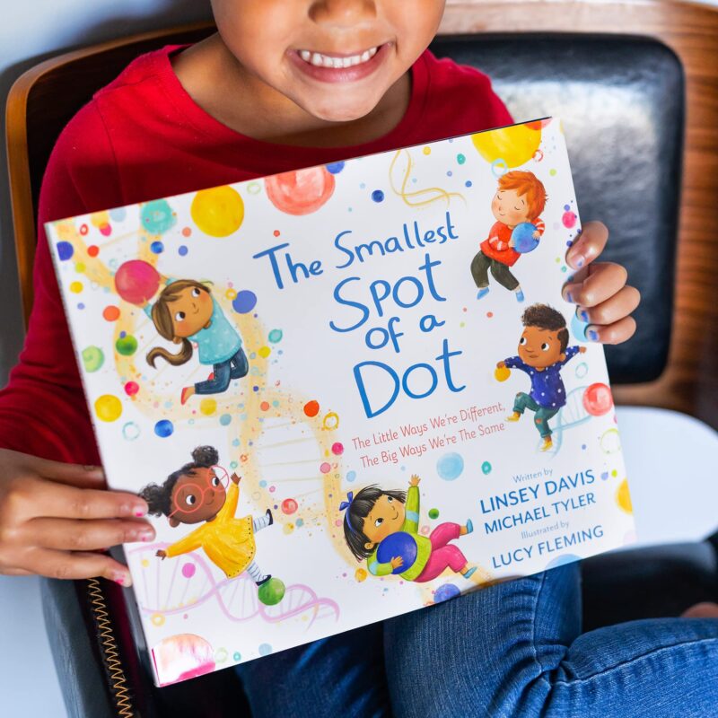 Child holding one of her first day of school books entitled The Spot of a Dot