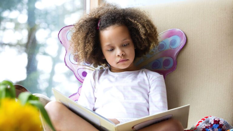 Child in butterfly wings with a book on her lap