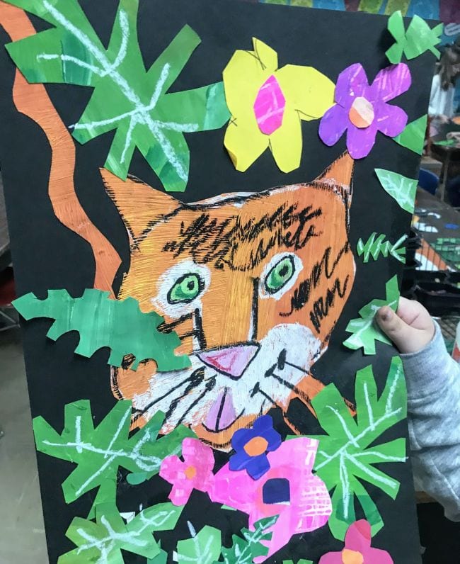 Textured painted tiger among construction paper leaves and flowers
