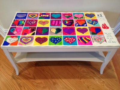 A white coffee table with hand painted heart tiles inlaid on the top