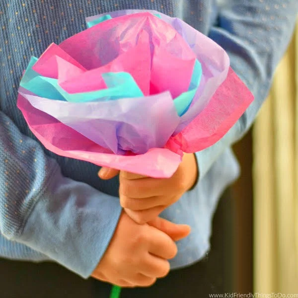A child holds a flower made from tissue paper