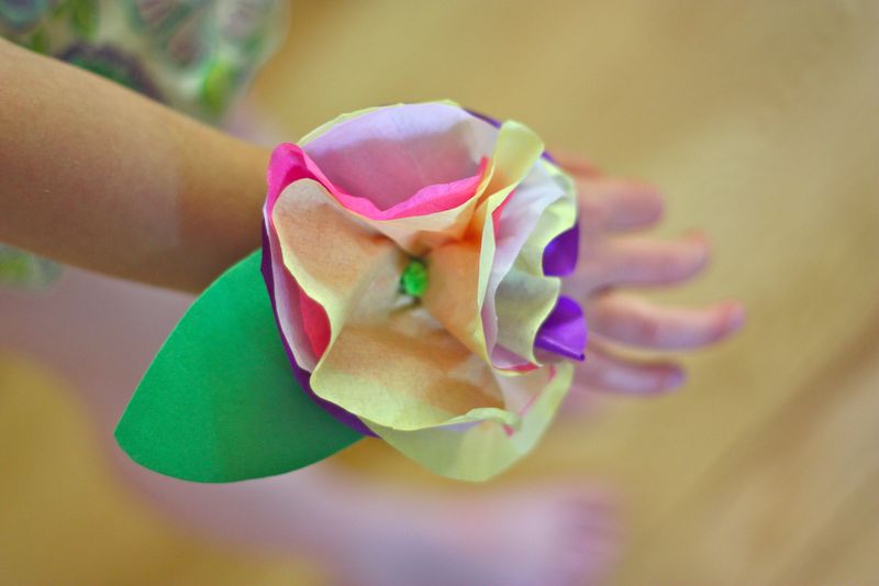 A hand is shown modeling a corsage made from tissue papers that look like flowers.