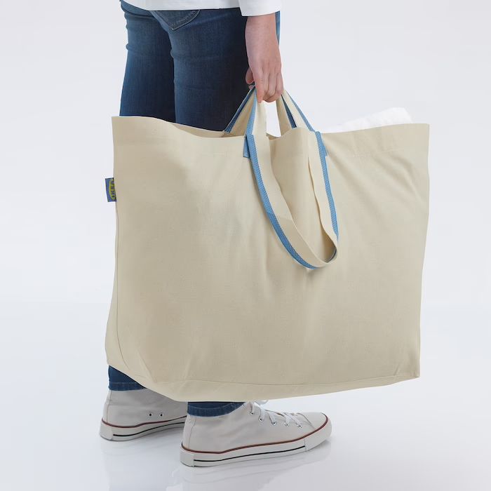 A woman is shown from the waist down holding a tote bag.
