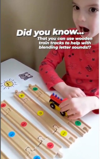 Child using toy trains to blend letter sounds