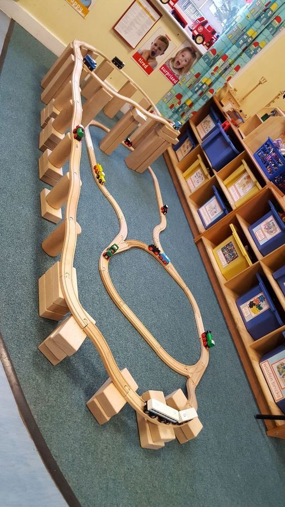 Wooden toy train tracks are assembled in a classroom with wooden blocks supporting them at various heights, , as an example of IKEA classroom supplies.