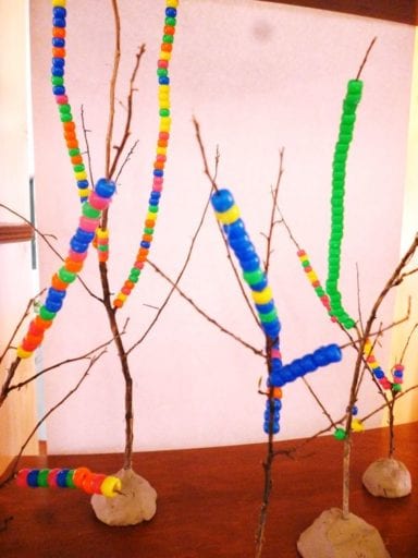 Twigs held upright with clay and strung with colorful plastic beads