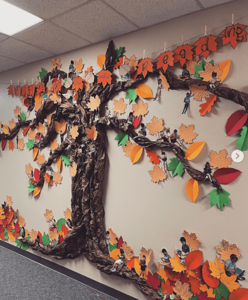 Fall bulletin boards feature trees like this 3-D one with . Cut out leaves adorn the branches and there are photos of the students reading that have been hidden around the tree.