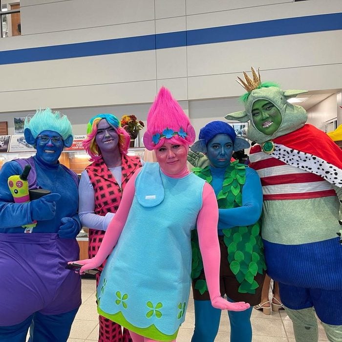 Teacher Halloween costumes like this one include five people dressed as troll dolls. Their skin is painted blue, purple, pink, and green and they have troll hair wigs.