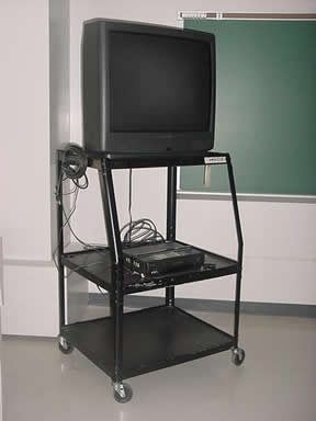 An old TV on a cart with wheels in a classroom