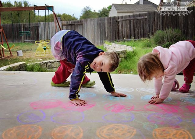 Kids playing sidewalk chalk Twister outside,s an example of gross motor activities.