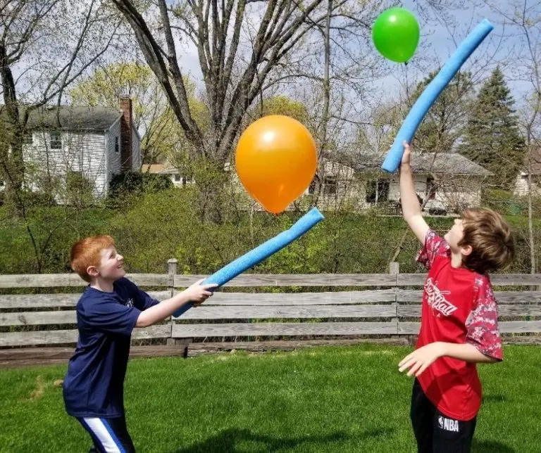 Two boys batting balloons with pool noodles as an example of team building activities for kids.