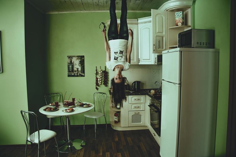 Woman hanging upside down from the ceiling in a kitchen