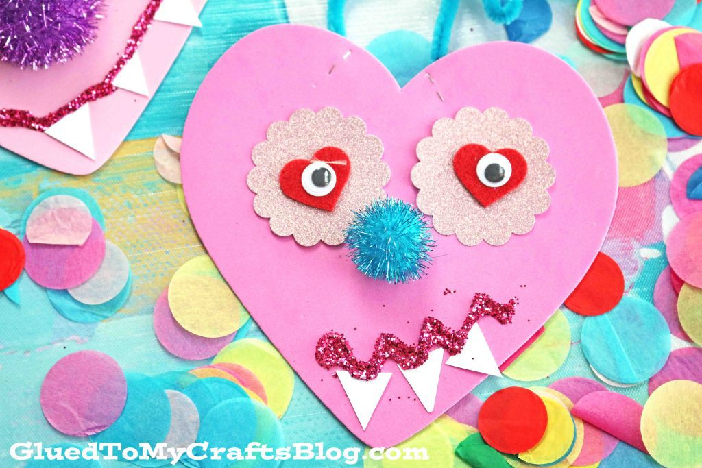 A Monster is created from a pink heart and other stickers, pom poms, and glitter. (Valentine's Day Crafts for Preschoolers)