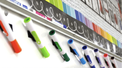 Dry erase markers attached to a whiteboard with velcro