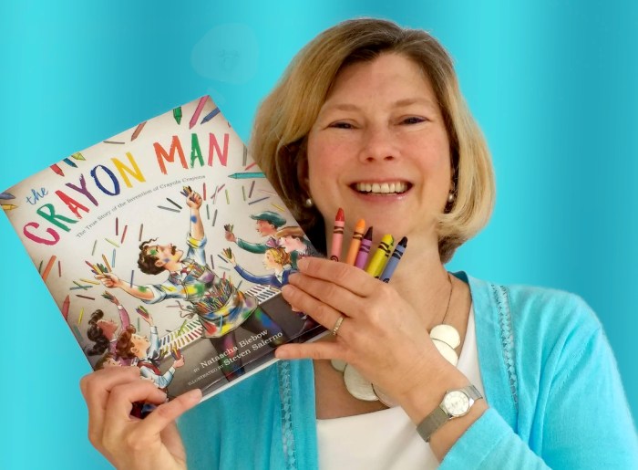 Children's author Natascha Biebow holding up her book, Crayon Man, and a handful of crayons. She does virtual author visits and other activities.