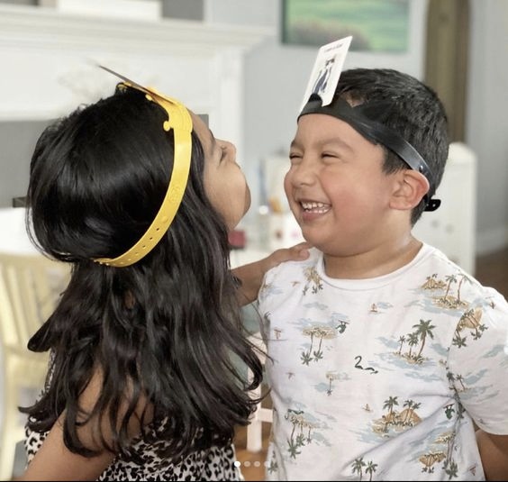 Two young students wearing head bands giggle at each other