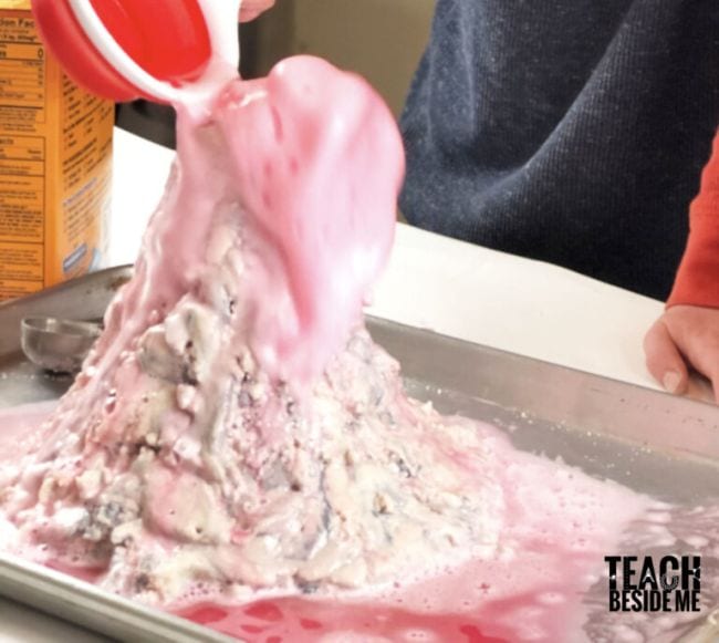 Student pouring vinegar into a salt dough volcano (Volcano Science Experiments)