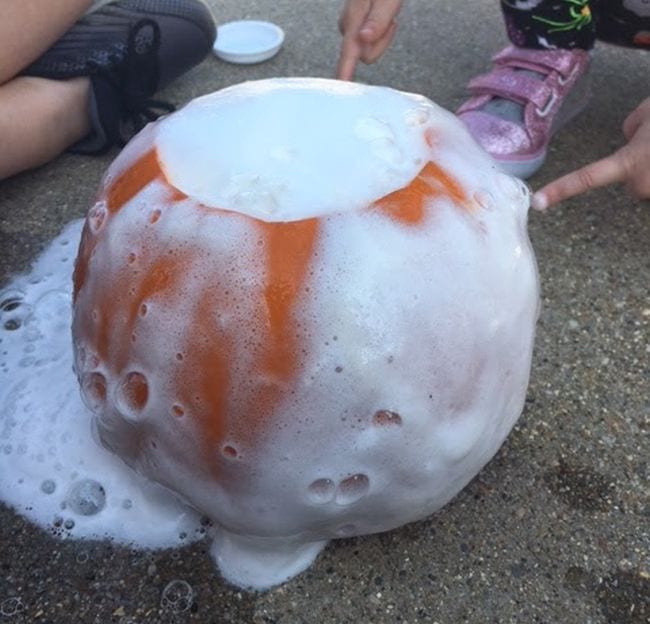 Children watching foam erupt from a pumpkin