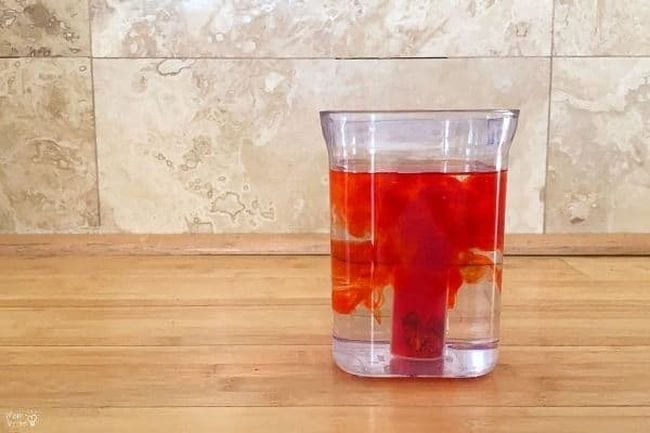 Red water forming a cloud in a glass of regular water