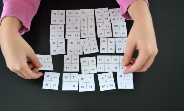 Dr. Seuss math activities- a child's hands framing a hundreds chart cut into 4x4 squares 