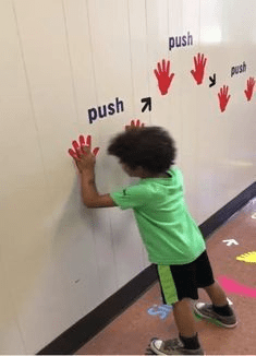 Kid putting his hands on interactive wall decals that say "push"
