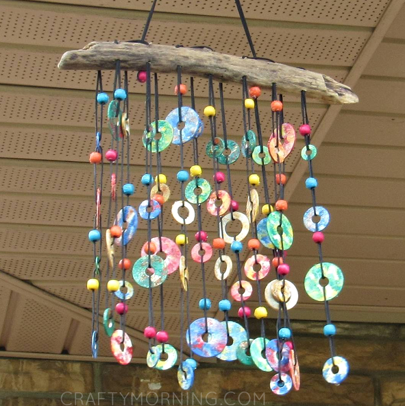 Painted metal washers dangle from a piece of driftwood