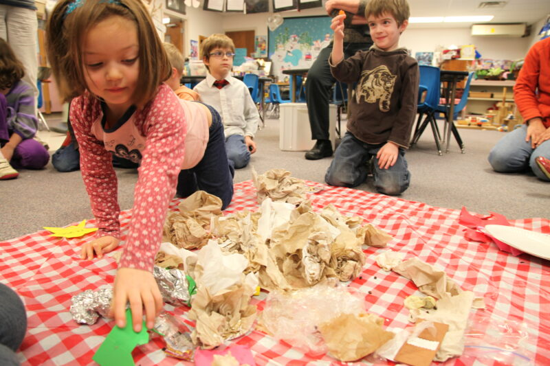 girl sifting through trash in a classroom for a green class idea