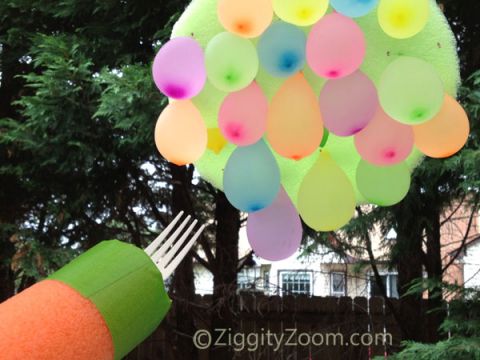 water squirter with a fork in the top pointed at a bunch of water balloons 