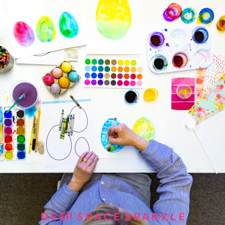 A child is seen painting Easter eggs with watercolor paints.