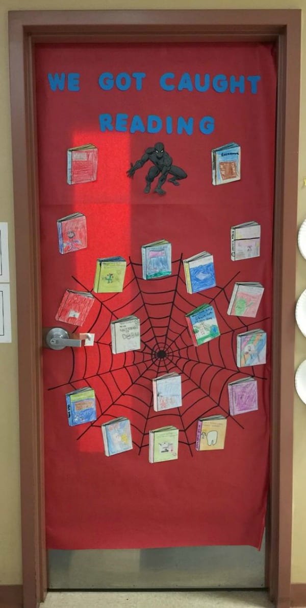 Fall bulletin boards include doors like this one that read "We got caught reading." There is a black spiderweb on a red background with cutouts of books that students have decorated all over the door. Spiderman is also on the door.