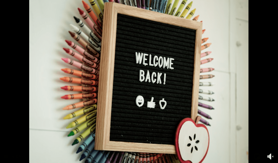 A black board with 'Welcome Back' surrounded by a rainbow of crayons
