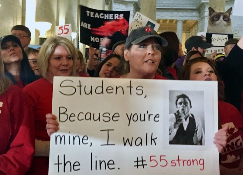 Teacher holding a sign walking in protest