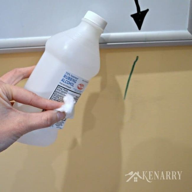 Person using alcohol and cotton ball to clean dry erase marker off the wall