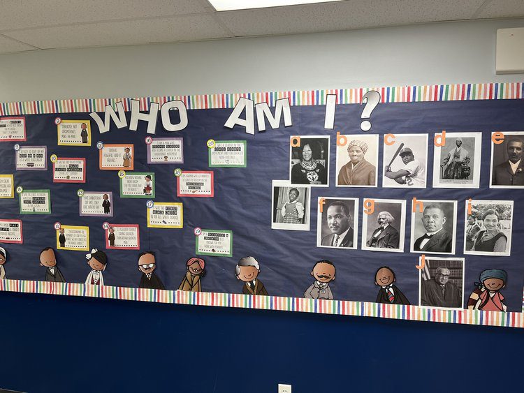 A bulletin board has boxes with text on them on the left side and pictures on the right side. The text on the top says Who Am I?