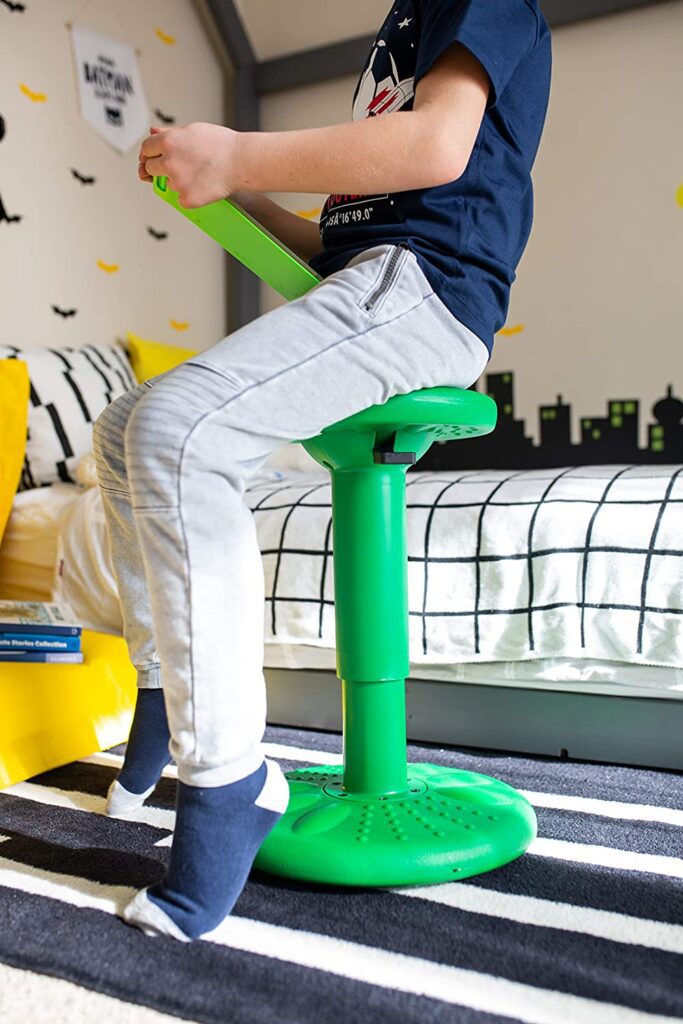 A person is seen sitting on an adjustable green stool.