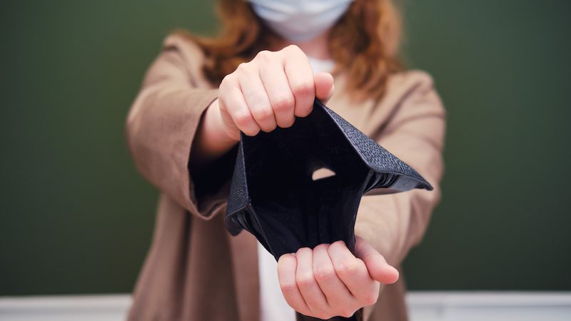 Teacher in medical mask holding empty wallet