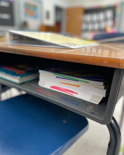 Inside of a student's desk with color-coded workbooks