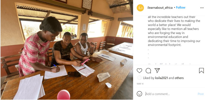 Teacher in Africa sitting at a table with two students doing work