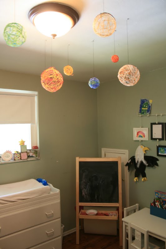 Planets made from yarn are shown haning from a ceiling (solar system projects)