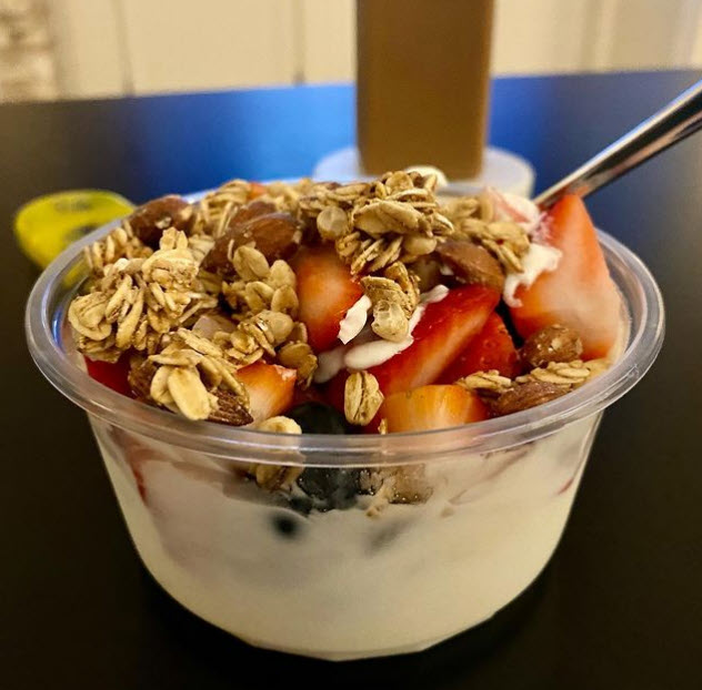 Plastic bowl with yogurt topped by fruit and granola